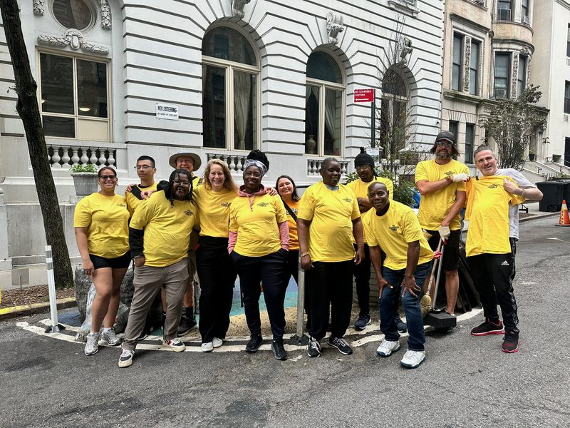 The long table set down W. 103rd Street, with neighbors gathered along its length, 2025